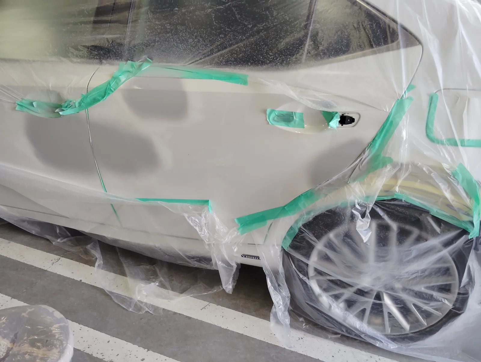 レクサスISの車体全体をビニールで覆い、塗装する左側面だけを露出させた養生
