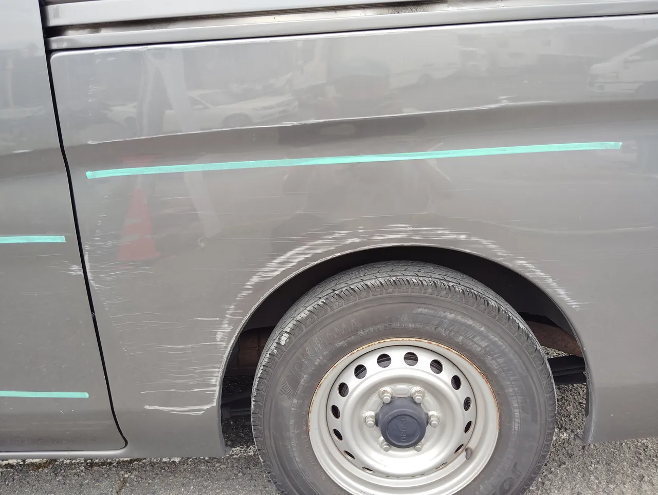 いすゞ・コモ 左リヤクォーターの後輪のまわりの擦り傷と、プレスラインのまわりの変形