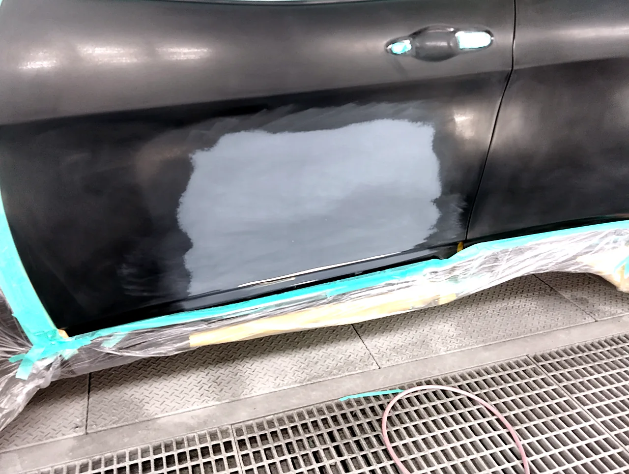 塗装ブースで足付けを終えたジープ チェロキーの左フロントドア。灰色のサフェーサーの部分とつやの消えた黒