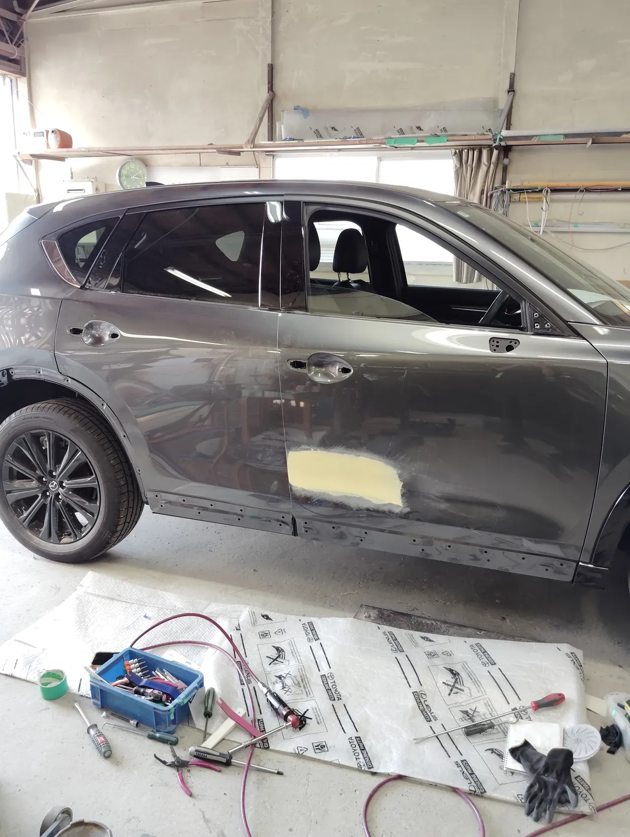 ドアミラー・ドアハンドル・モール類を外したマツダ CX-5 の右側面。右フロントドアにパテ