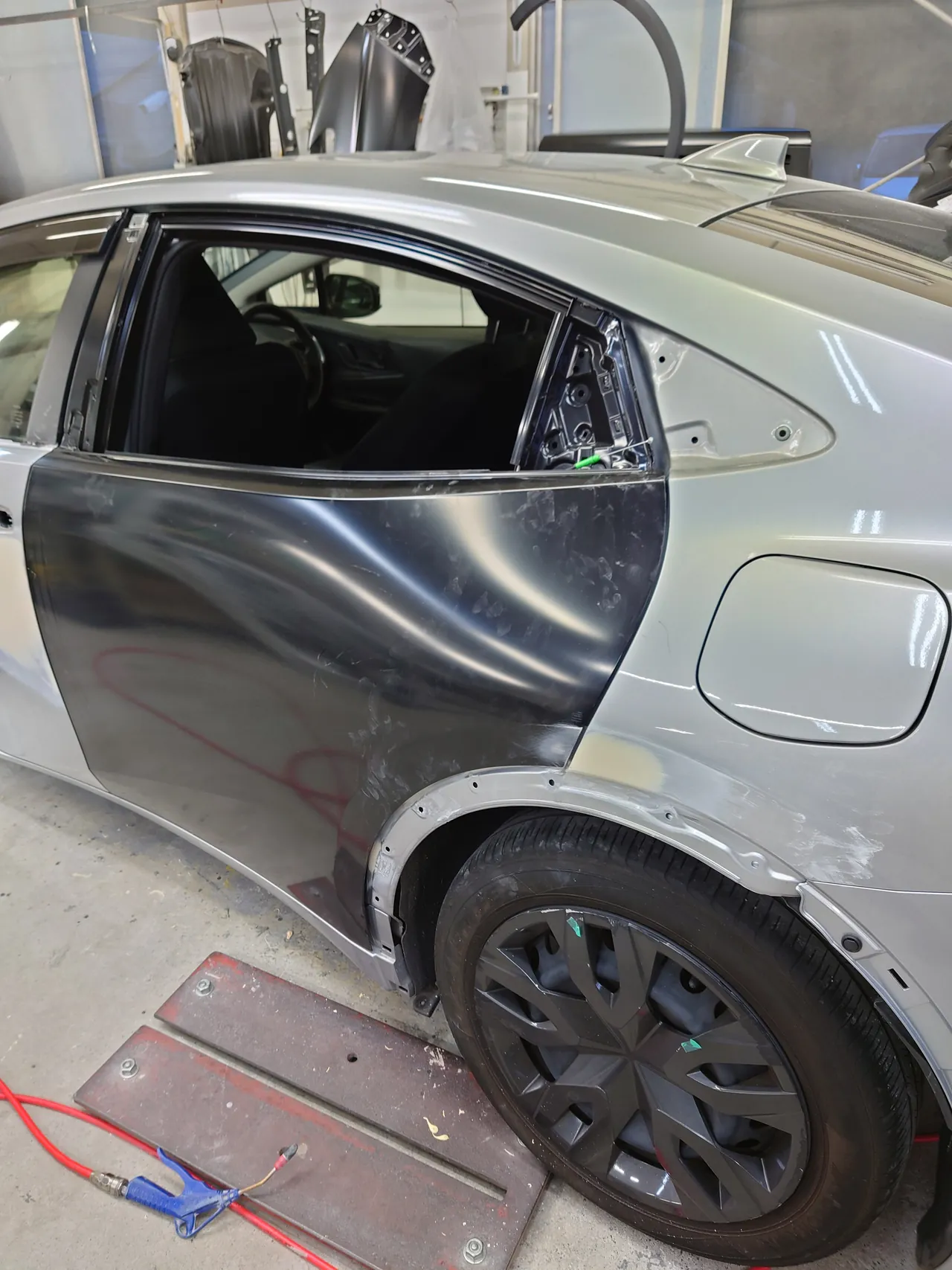 色を付ける前の黒い新品の左リヤドアを車体に取り付けたプリウス（後ろ寄りから）。クォーターにはパテ