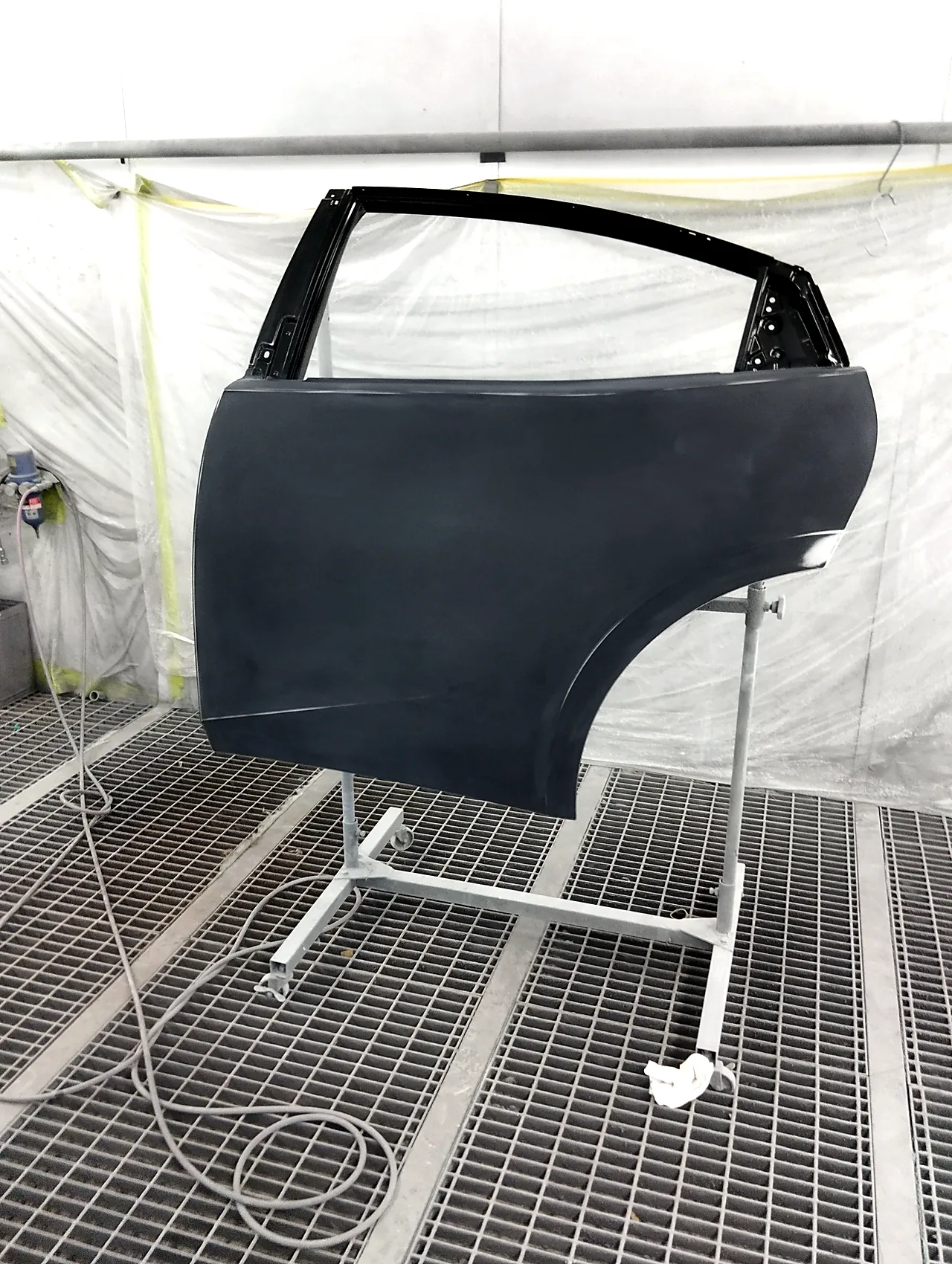 ブースの中でスタンドに載せた、まだ黒い新品のプリウス左リヤドア（塗る前）