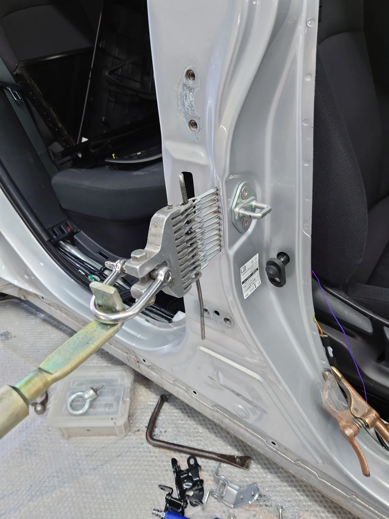 カローラツーリングの右センターピラー。一列に溶接した小さな金具を、多連フックの引き出し具でまとめてつかんで引く