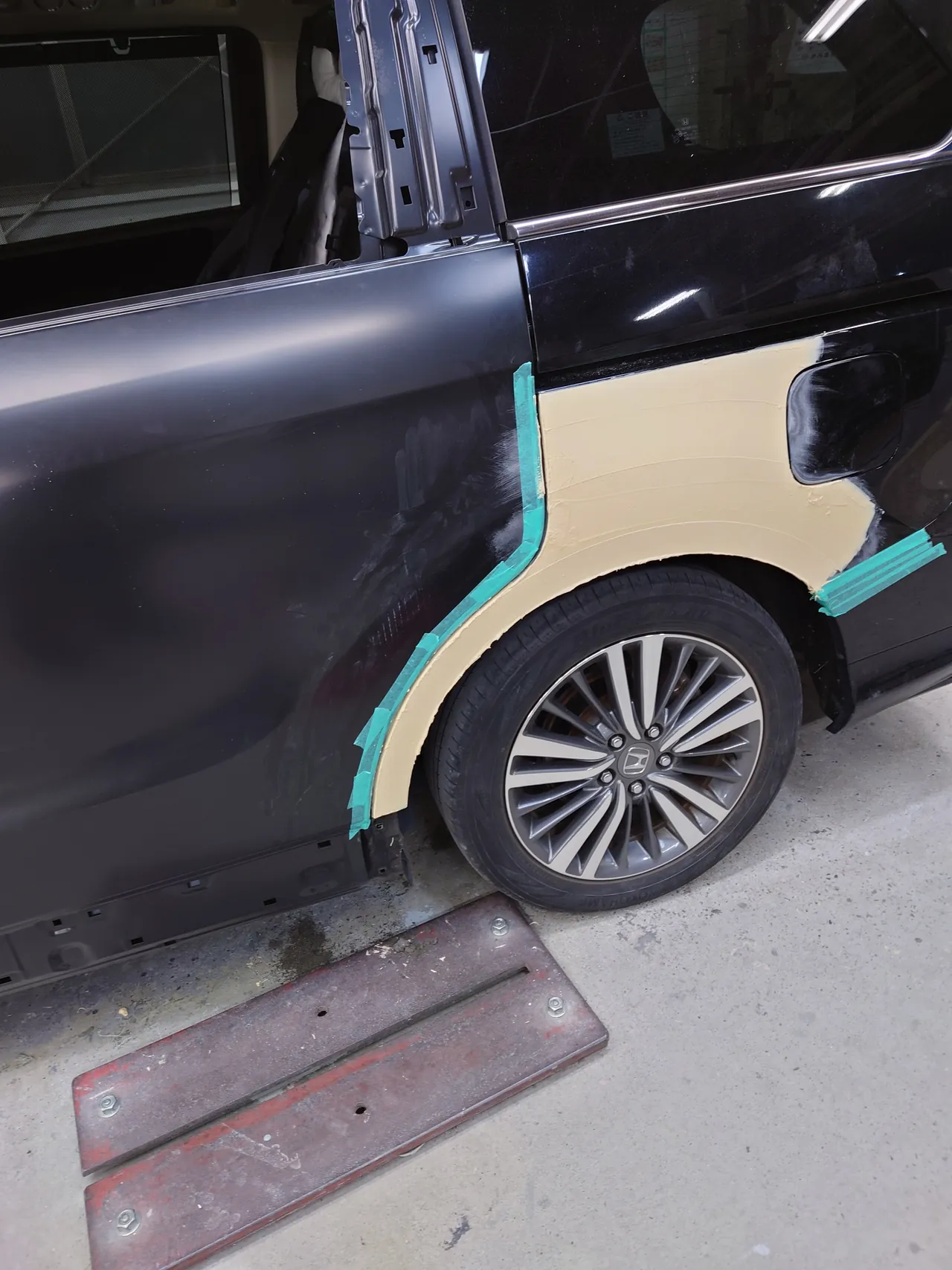塗る前の新品の左スライドドア(窓ガラスなし)を車に付けた状態で、オデッセイの左リヤクオーターにクリーム色のパテ