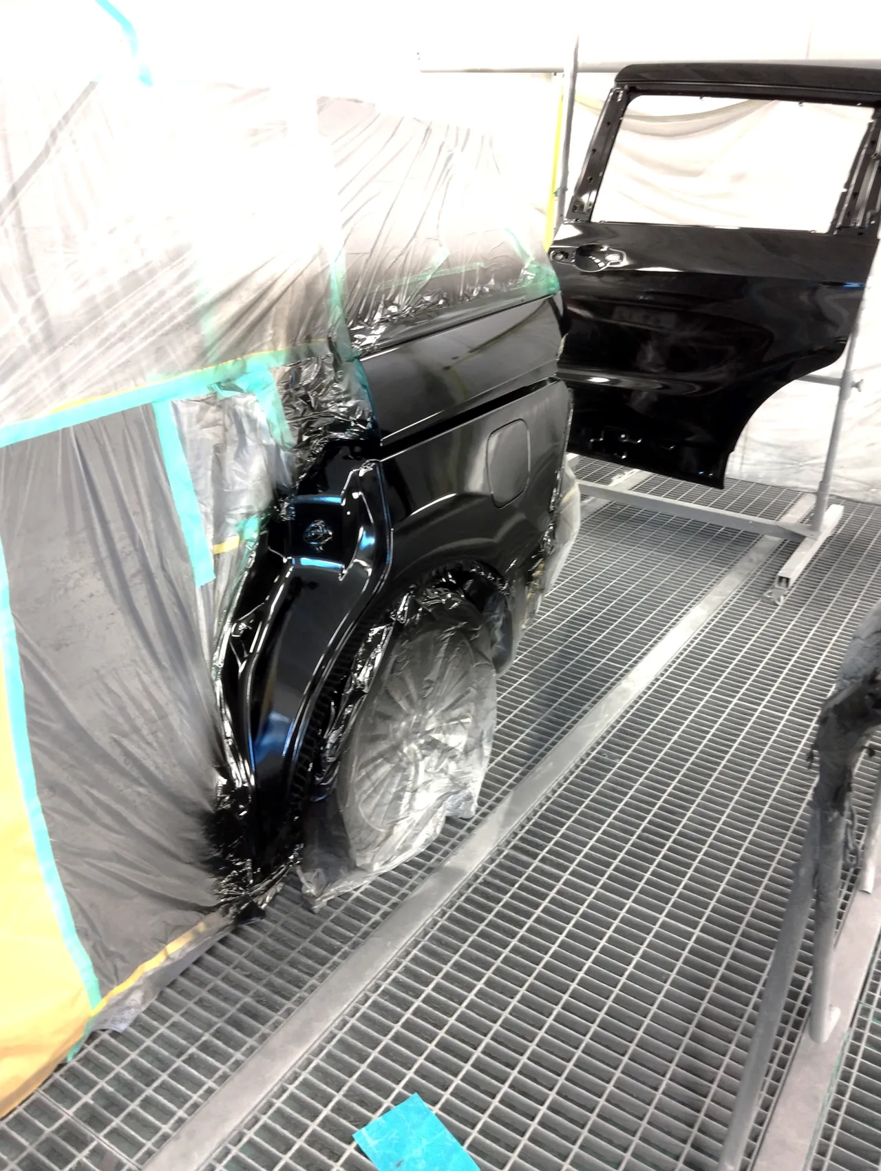 塗装ブースでNH731Pの黒に塗り上げたオデッセイの左リヤクオーターと、奥の台に立てた新品の左スライドドア