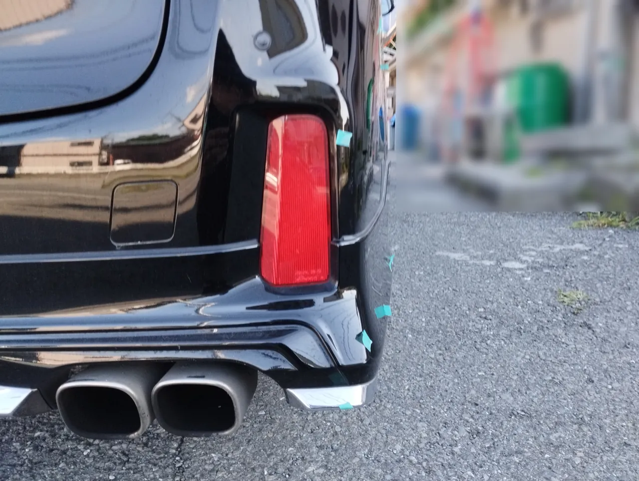 後ろから見た30系アルファードの右の角。反射板の横からマフラーの横のメッキの飾りまで緑のテープ（修理前）