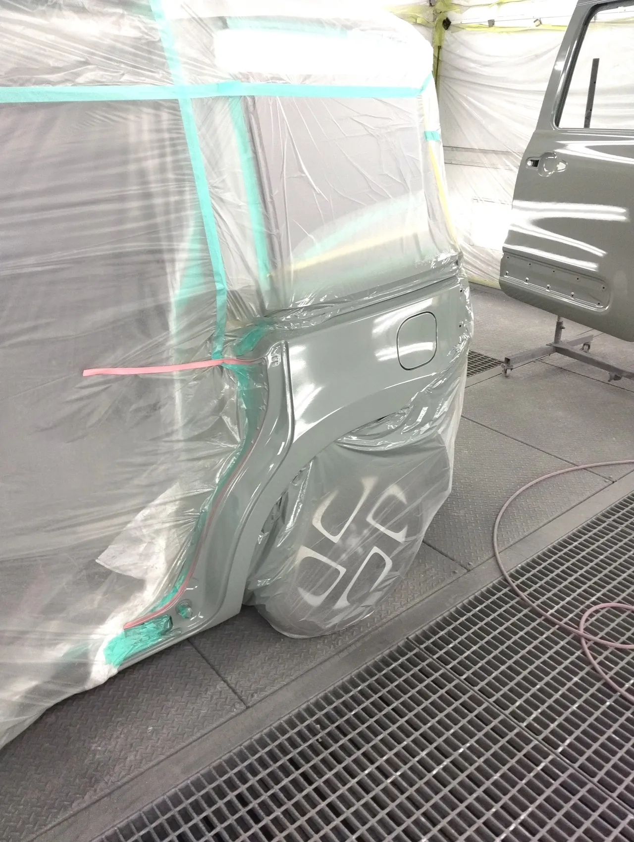 塗装ブースでカラー番号6X3に塗り上げたシエンタの左リヤクォーターと、奥の台に立てた交換用の左スライドドア