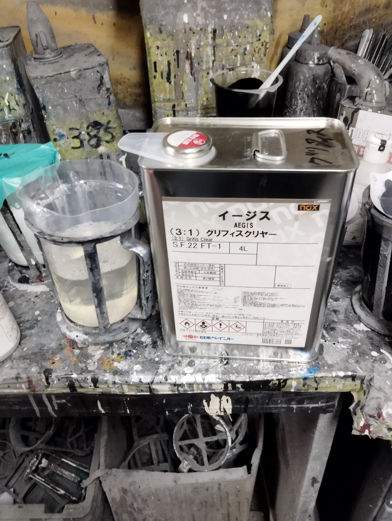 作業台に置かれたクリヤーの缶。40系アルファードの202の上に重ねた nax イージス（3:1）グリフィスクリヤー（日本ペイント）