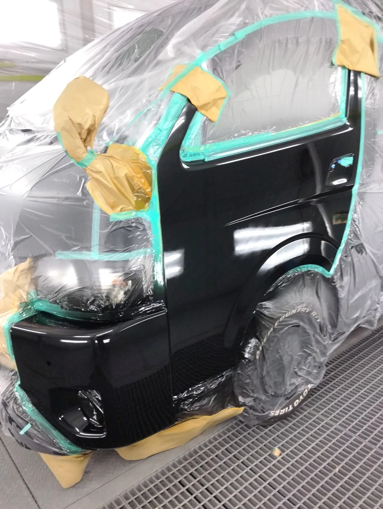 カラー番号209で塗装し、クリヤーまで終えたハイエースの左フロントドアとバンパー左角(塗装ブース)