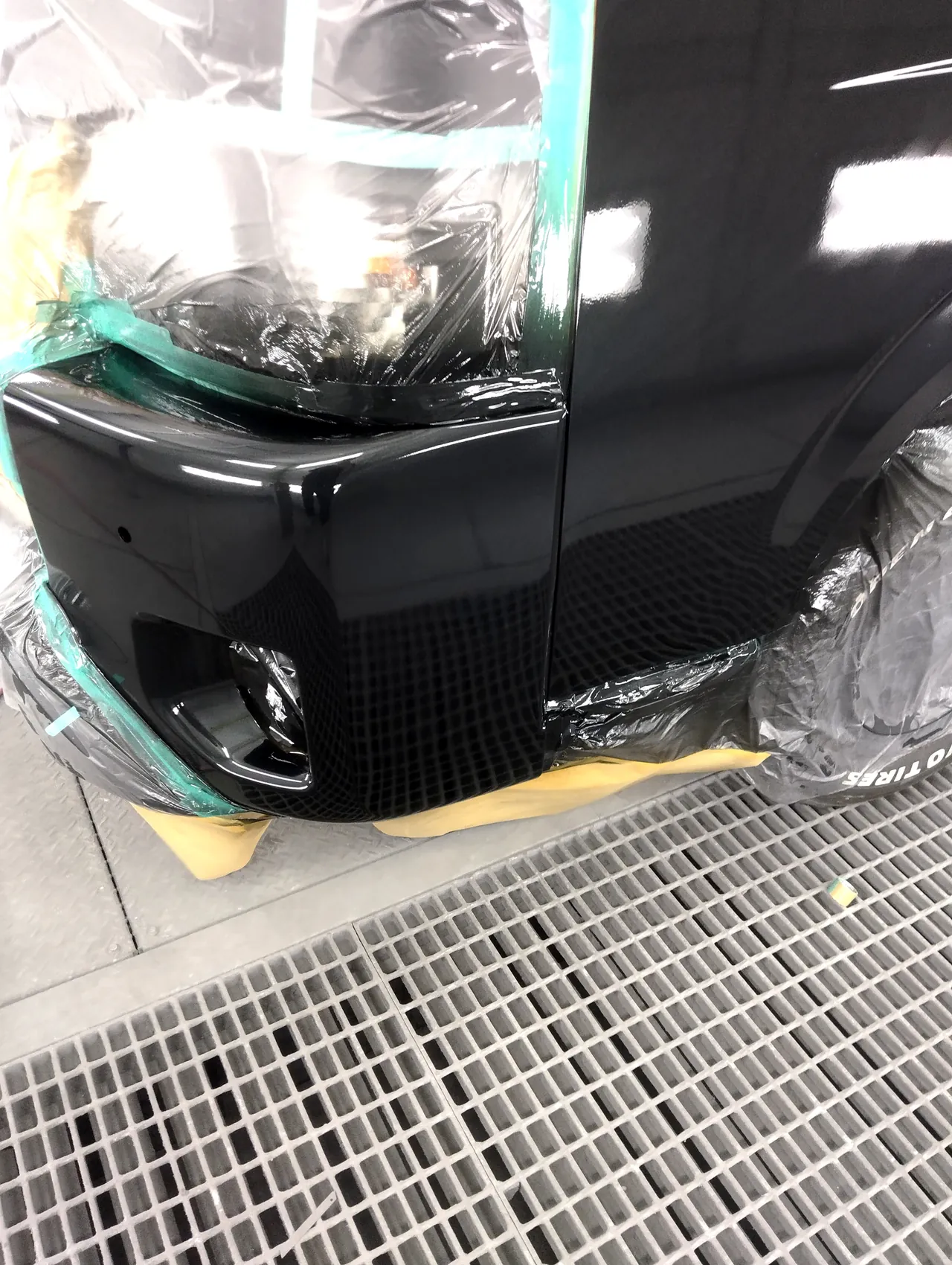 クリヤーのあとのハイエースのバンパー左角と左フロントドアの前下。床の網の目が映り込む