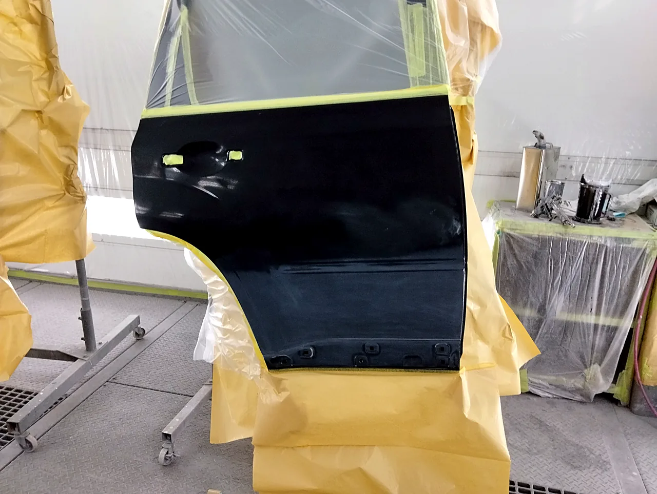 塗装ブースのスタンドに立てた日産 T31エクストレイルの右リヤドア（塗る前）。取っ手の穴にテープ