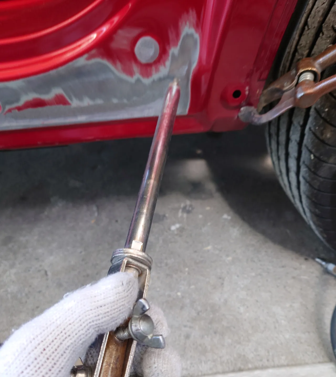 マツダ CX-5のサイドシルの後ろの端。塗装をはがした鉄板に溶接式の引き出し工具の先を当て、右にアースのクランプ