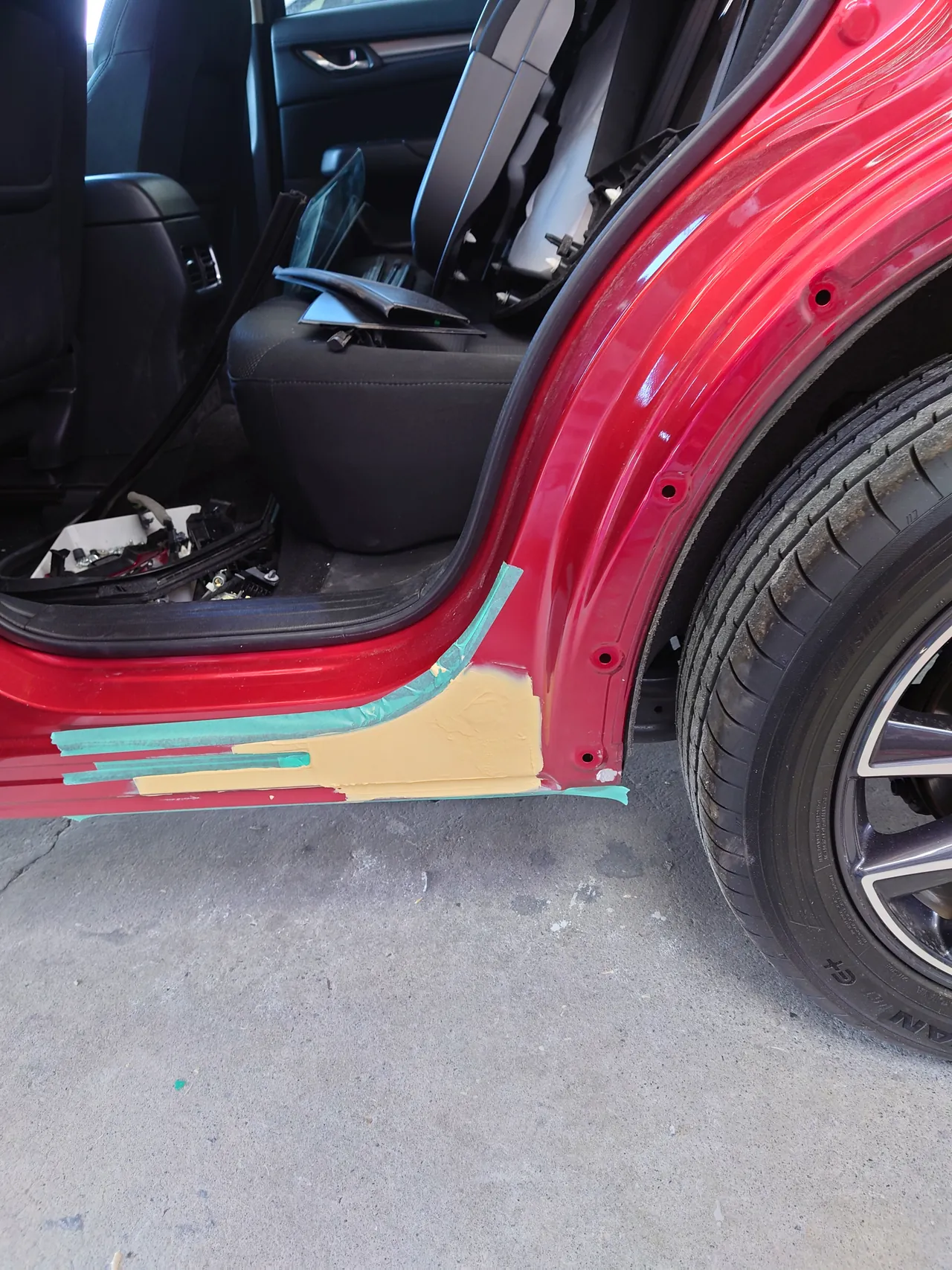 マツダ CX-5のサイドシルの後ろの端に付けたクリーム色のパテ。テープで範囲を区切っている