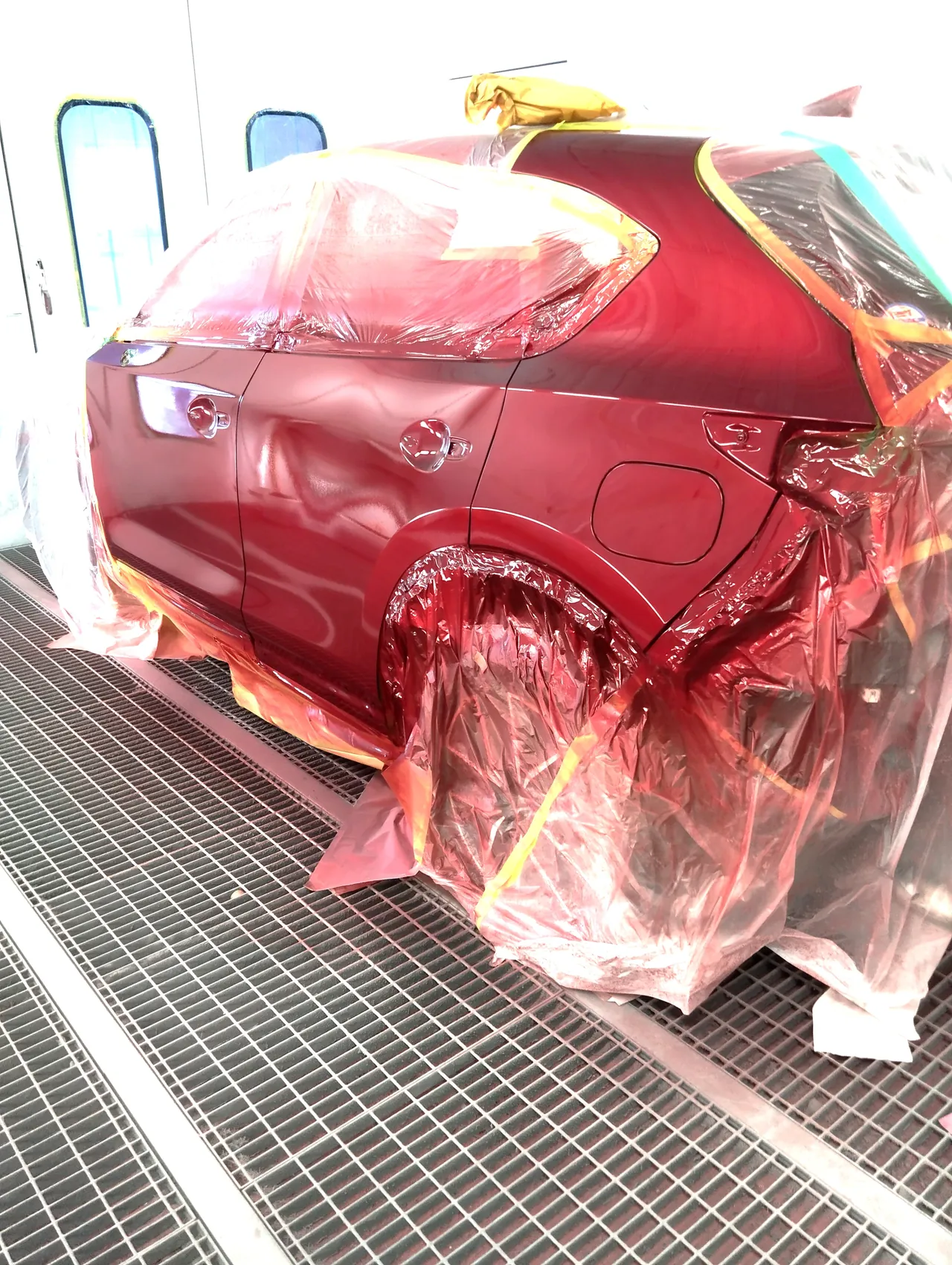 塗装を終えたマツダ CX-5の左リヤドアと左リヤフェンダー（46V）。まわりのビニールに赤い塗料の霧