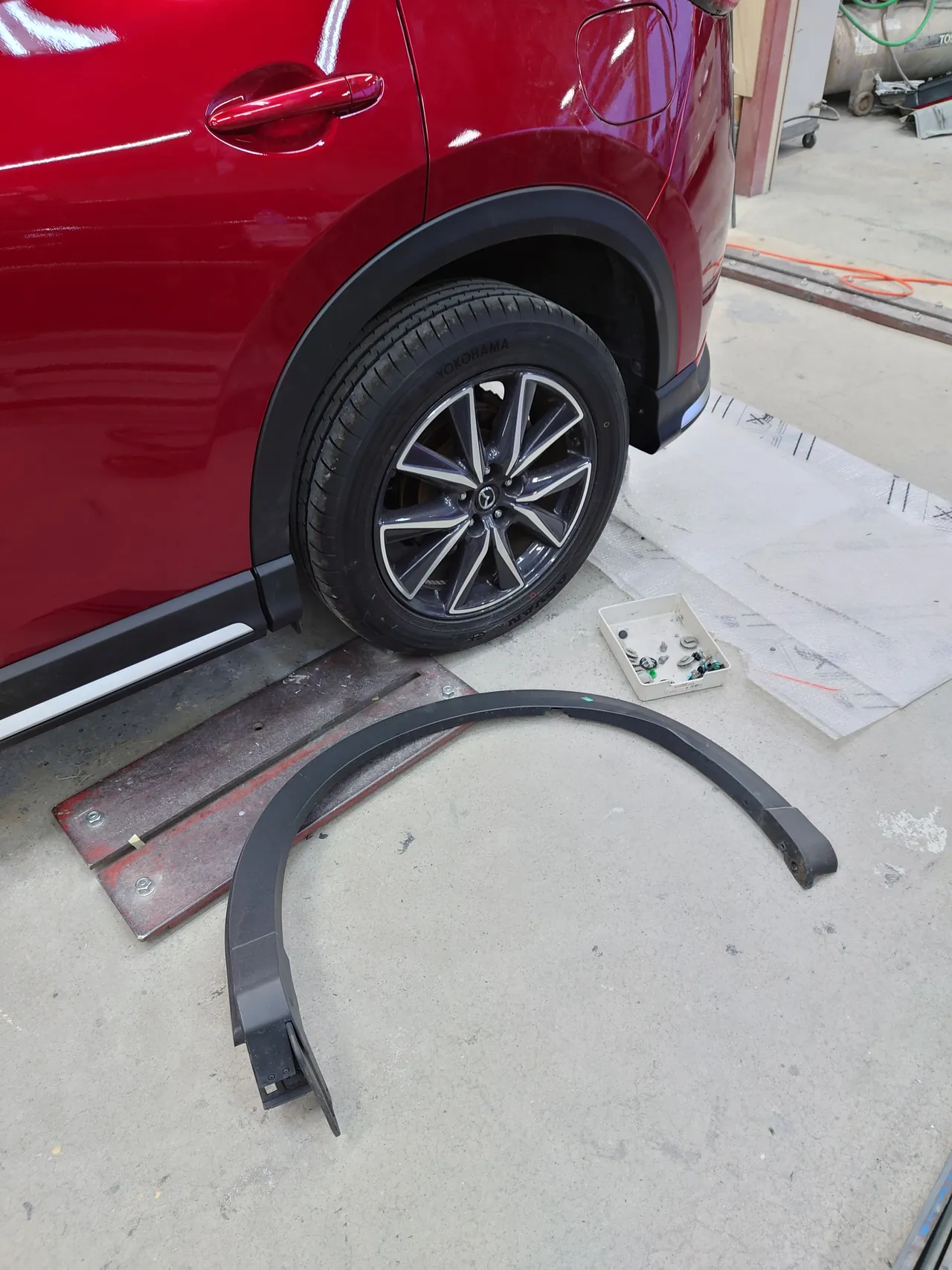 新しいホイールアーチのモールを付けたマツダ CX-5の左後輪まわり。床に目印のテープが残る外したモール