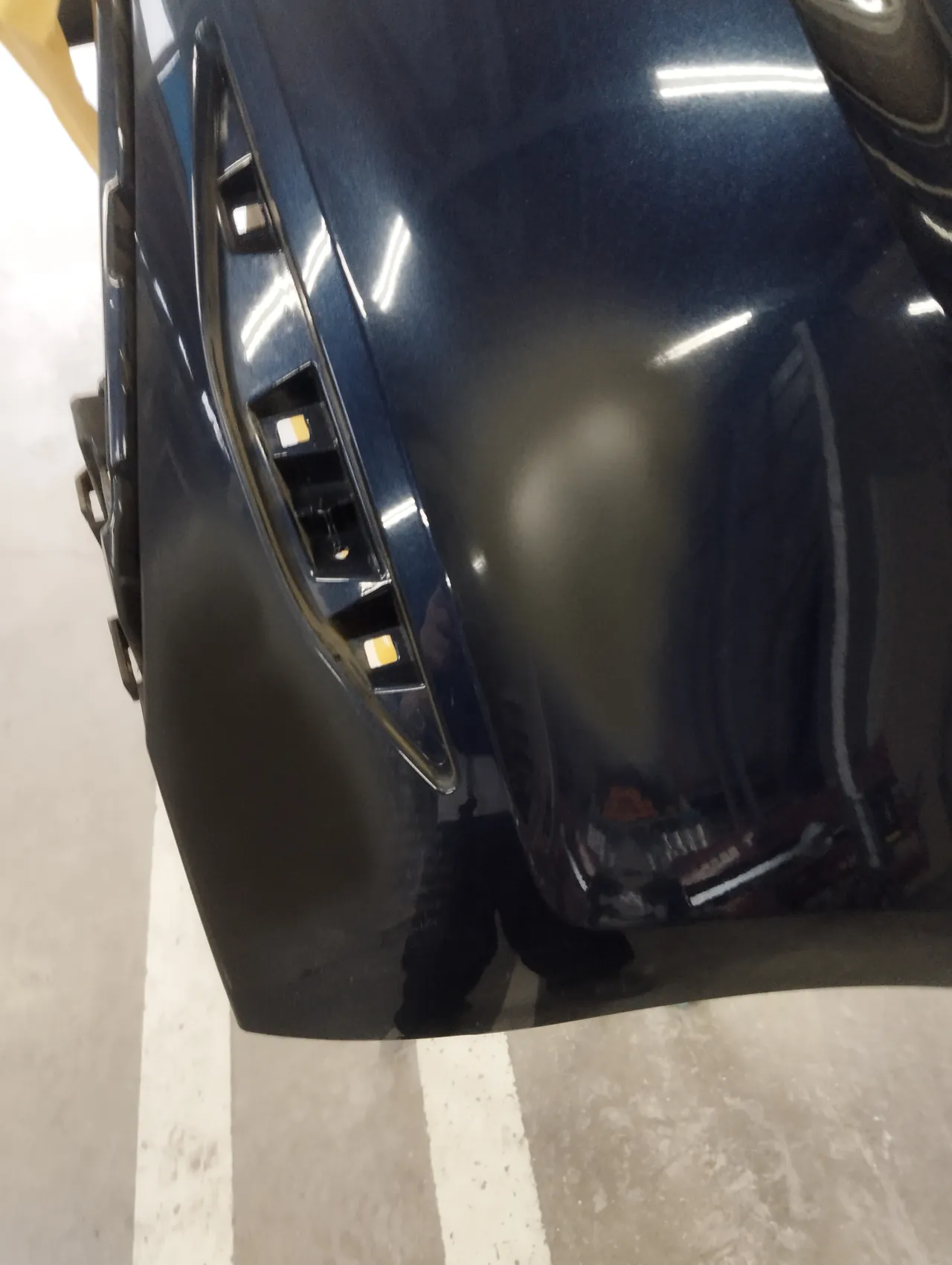 ゴルフ7のリヤバンパーの角。黒っぽい艶消しのサフェーサーを入れた所と、元の艶のある紺が残る所