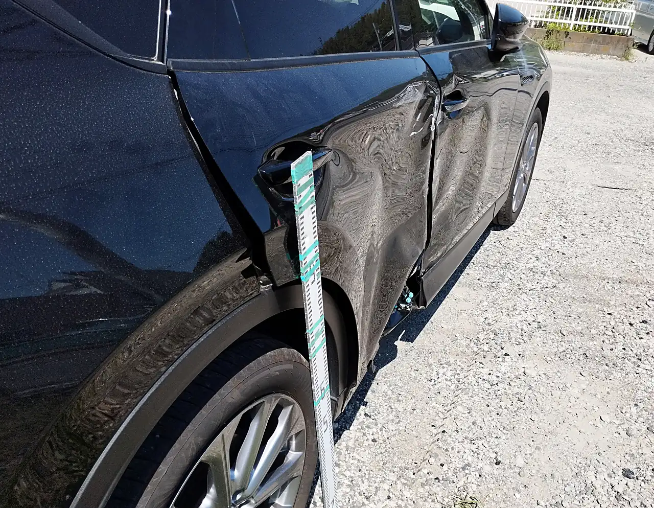 CX-60の右リヤドアの後ろ寄り。外側のハンドルのまわりから映り込みがゆがむ所に目盛りの棒（修理前）