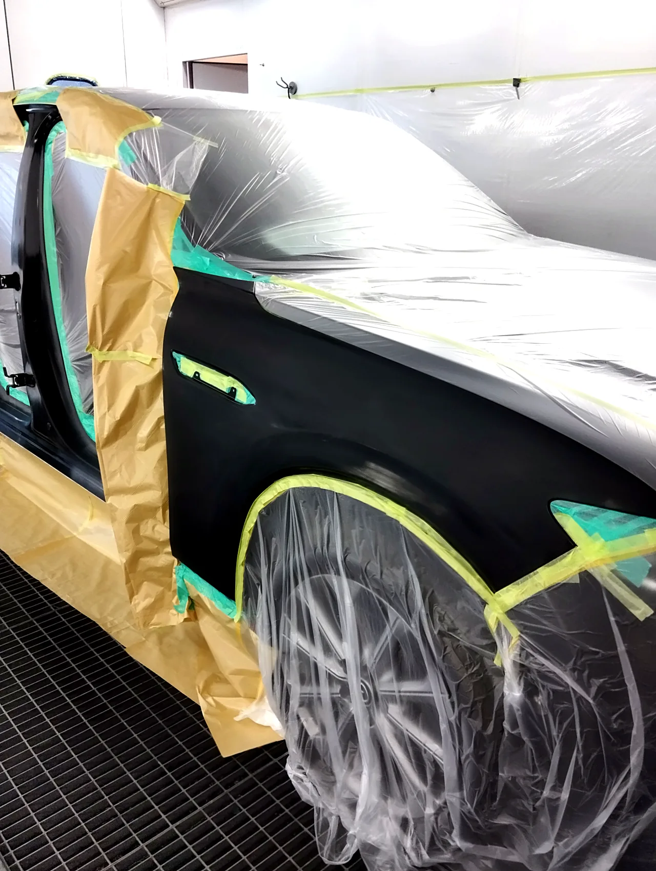 塗る前のマツダ CX-60の右前フェンダー。つやを研ぎ落とし、ドアの開口部は紙、ボンネットとタイヤにはビニールをかぶせる（塗装ブースの中）