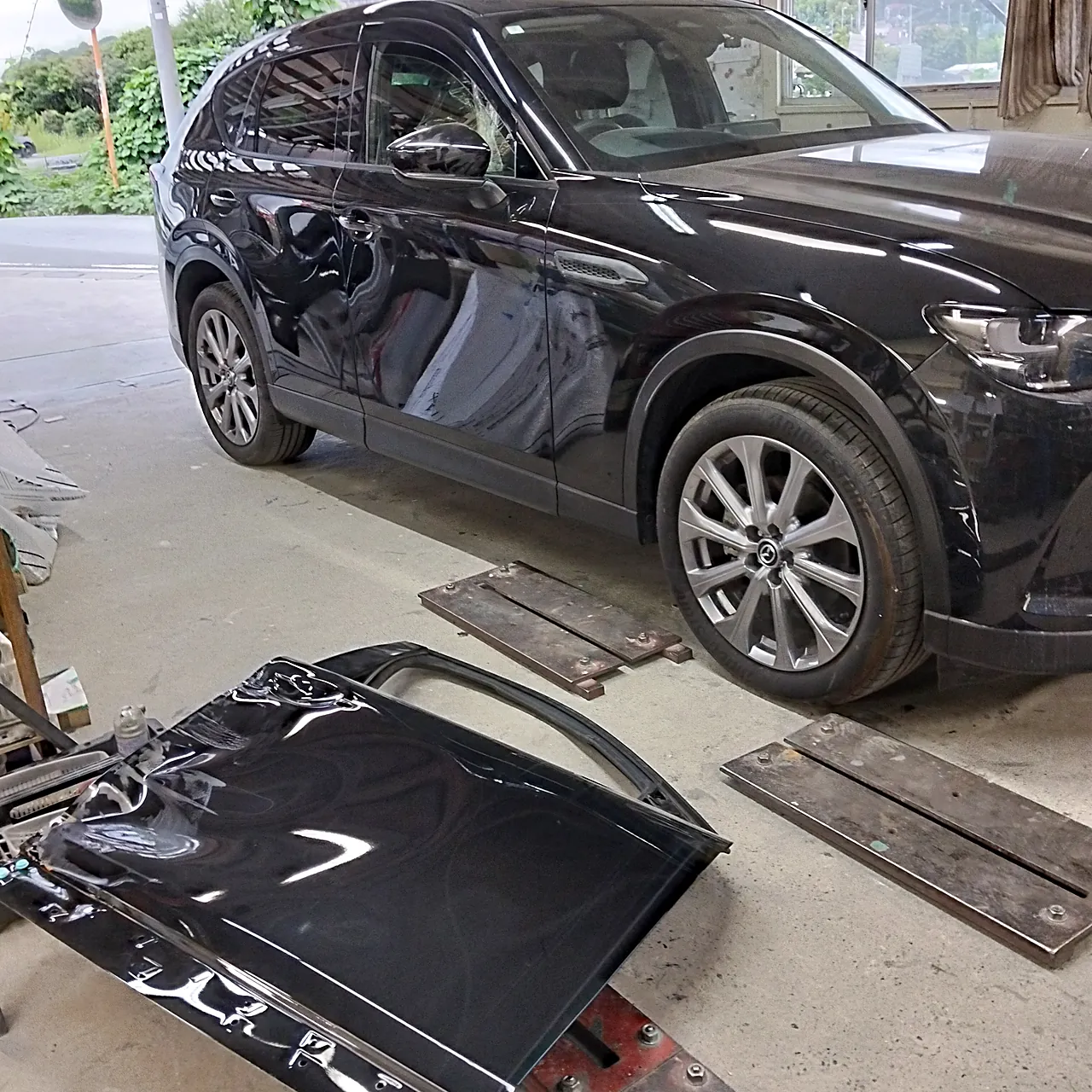 組み上がったマツダ CX-60の右前と、床に置いた外した元の右前ドア（工場の中）