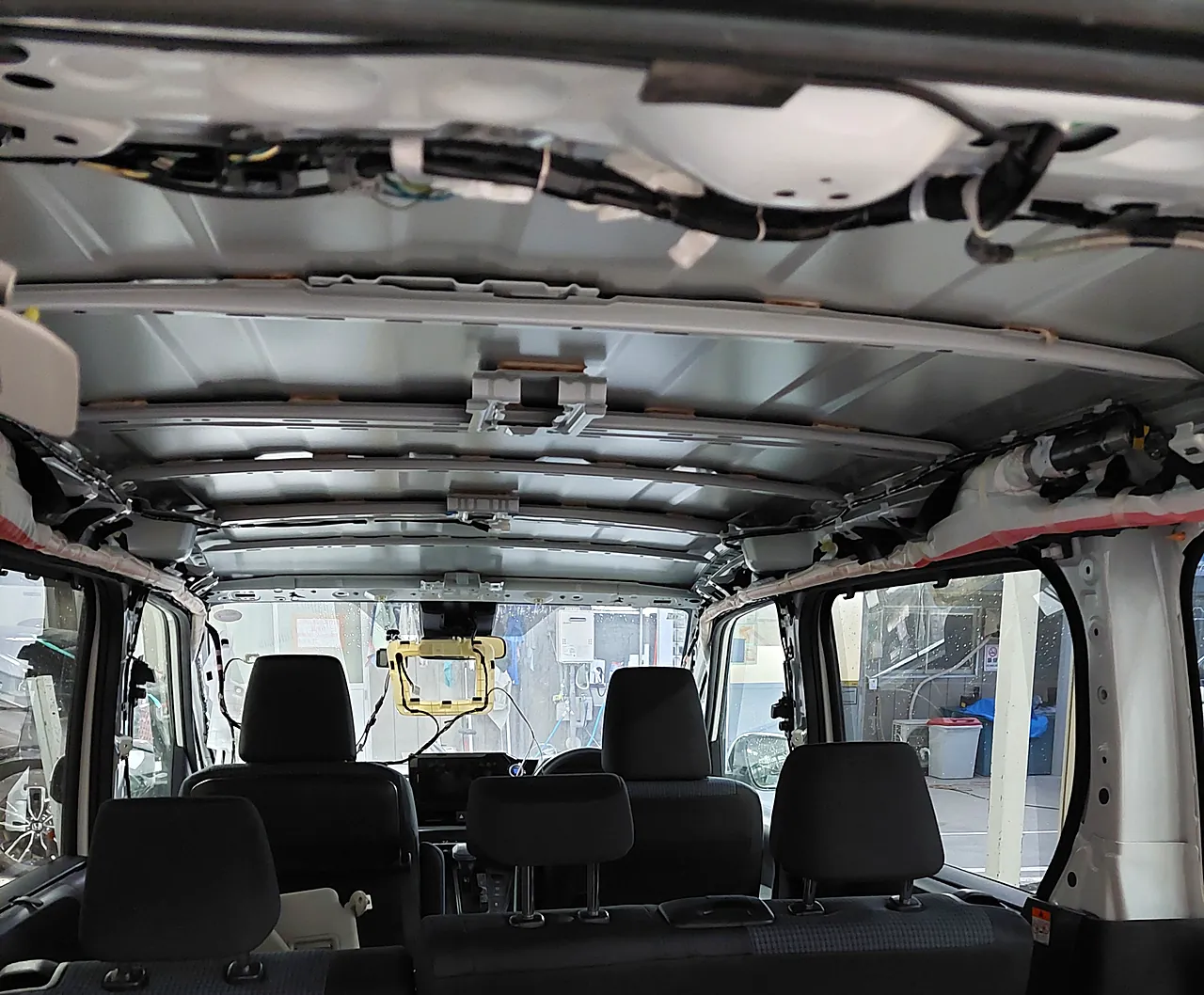 天井の内張りを全部外した90系ノアの車内。屋根の裏の鉄板と、前後に並ぶ梁が見える