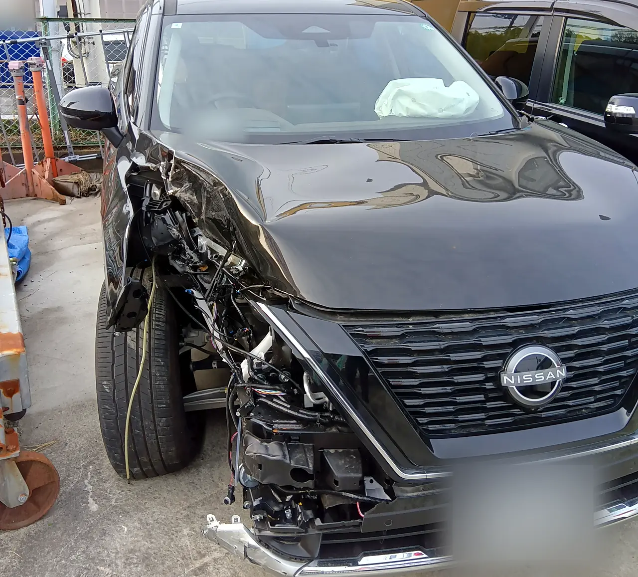 修理前のエクストレイル（T33）を正面のやや右から。右ヘッドランプがなく、ボンネットの右前がつぶれ、ガラス越しに開いた助手席のエアバッグ