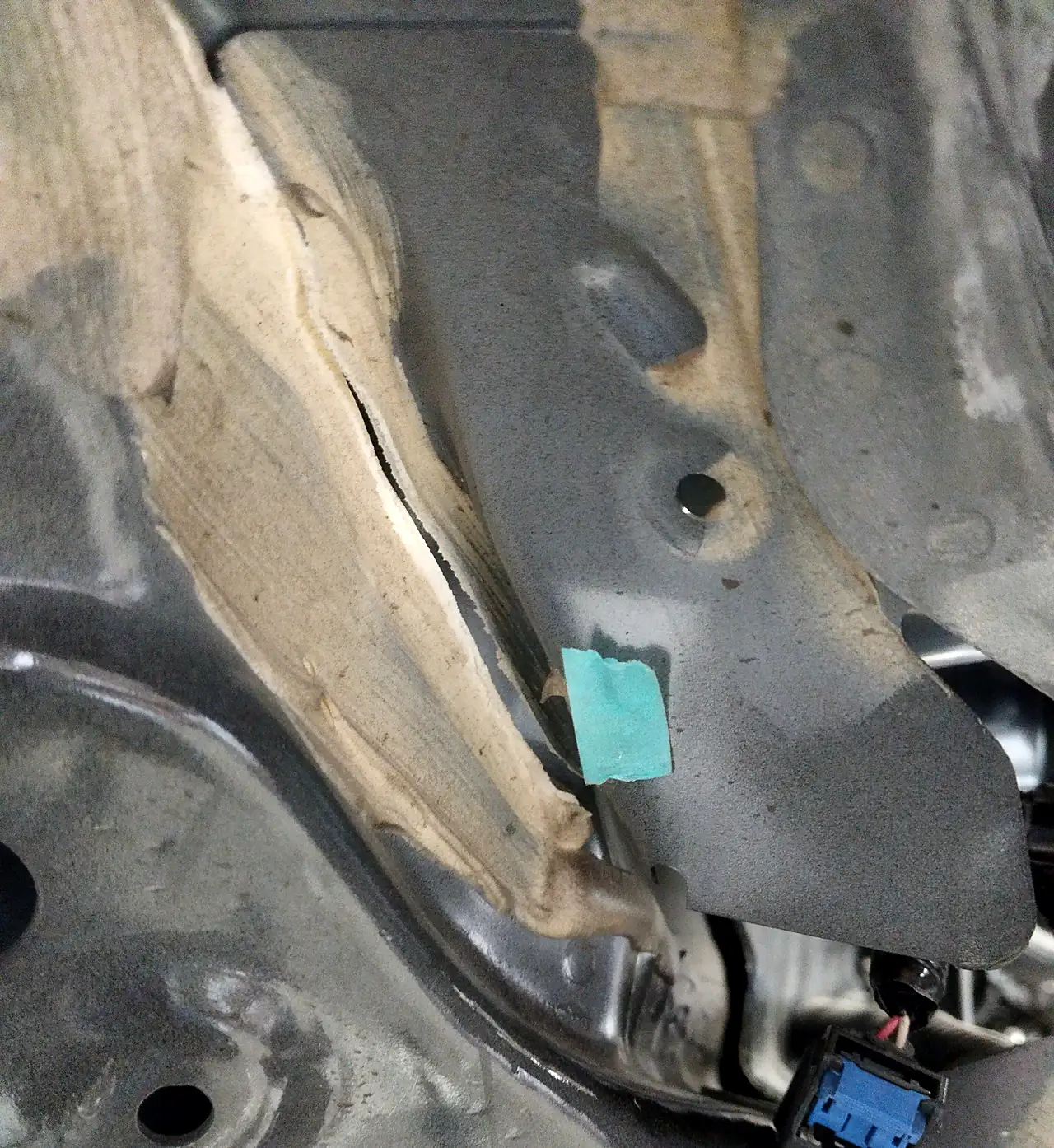 エクストレイルの前まわりの車体のつなぎ目。シーラーが割れてずれた所に水色のテープの印
