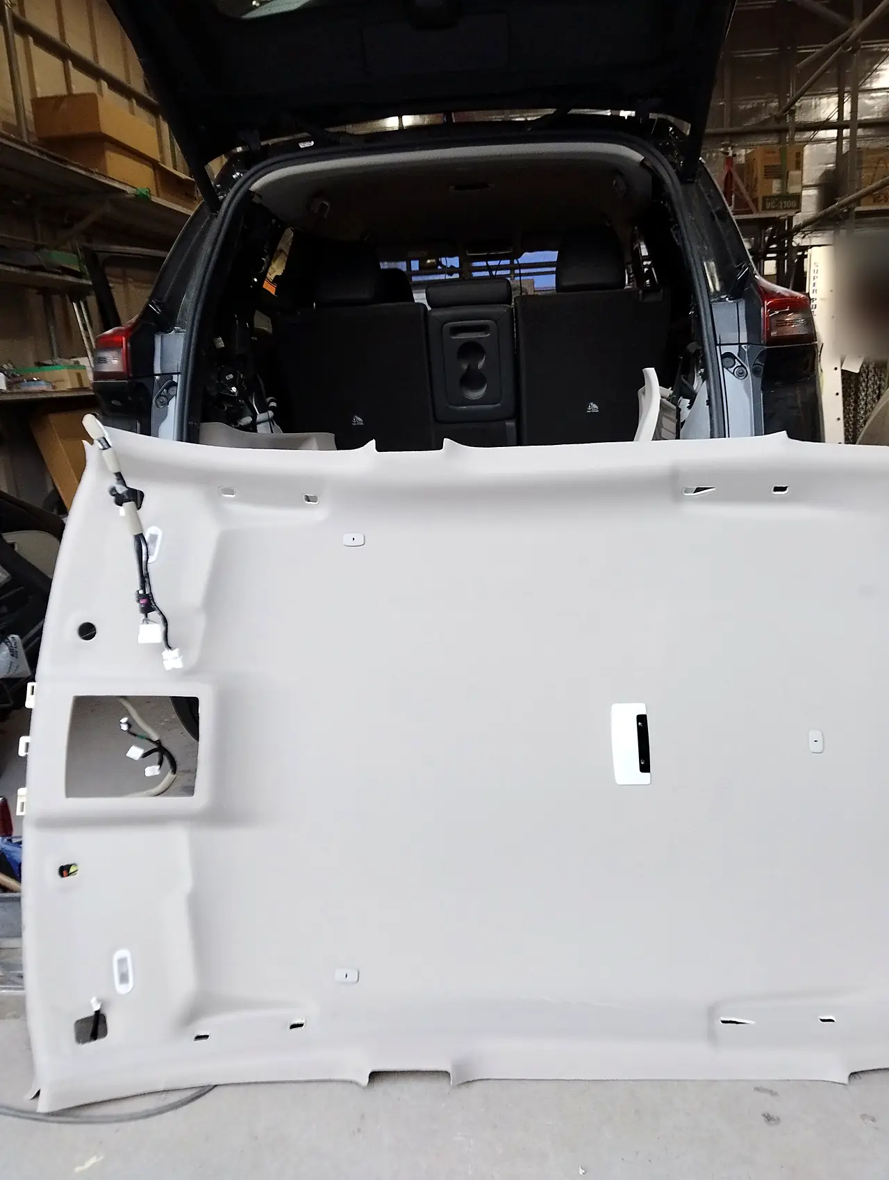 エクストレイルの荷室から、取り寄せた天井の内張りを車内へ入れるところ