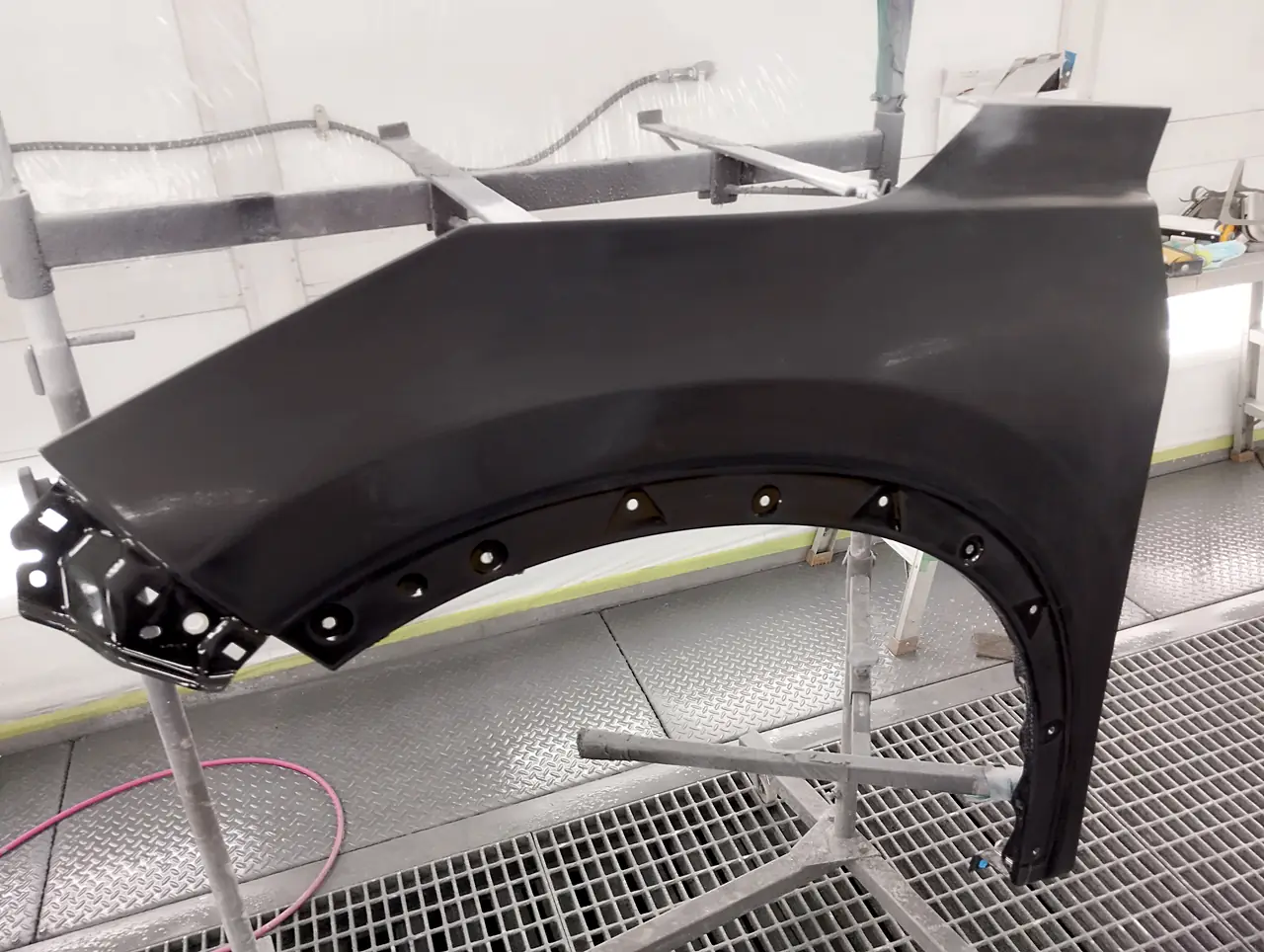 塗装ブースのスタンドに立てたエクストレイルの左フェンダー。表面を研いでつやを消した状態（足付け）