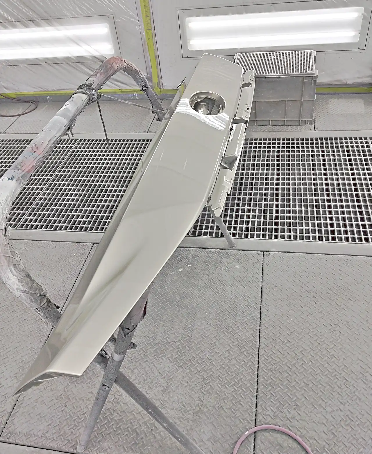 塗装ブースの台の上で、4X8に塗り終えたレクサスRXのバックドア上部パネル。エンブレムの穴と、照明の映り込み（塗装後）