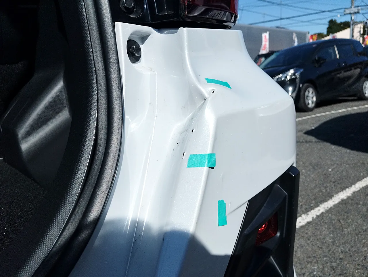 バックドアを開けたライズの開口部の右の縁。鋭い線の入ったへこみと緑のテープの印（修理前）
