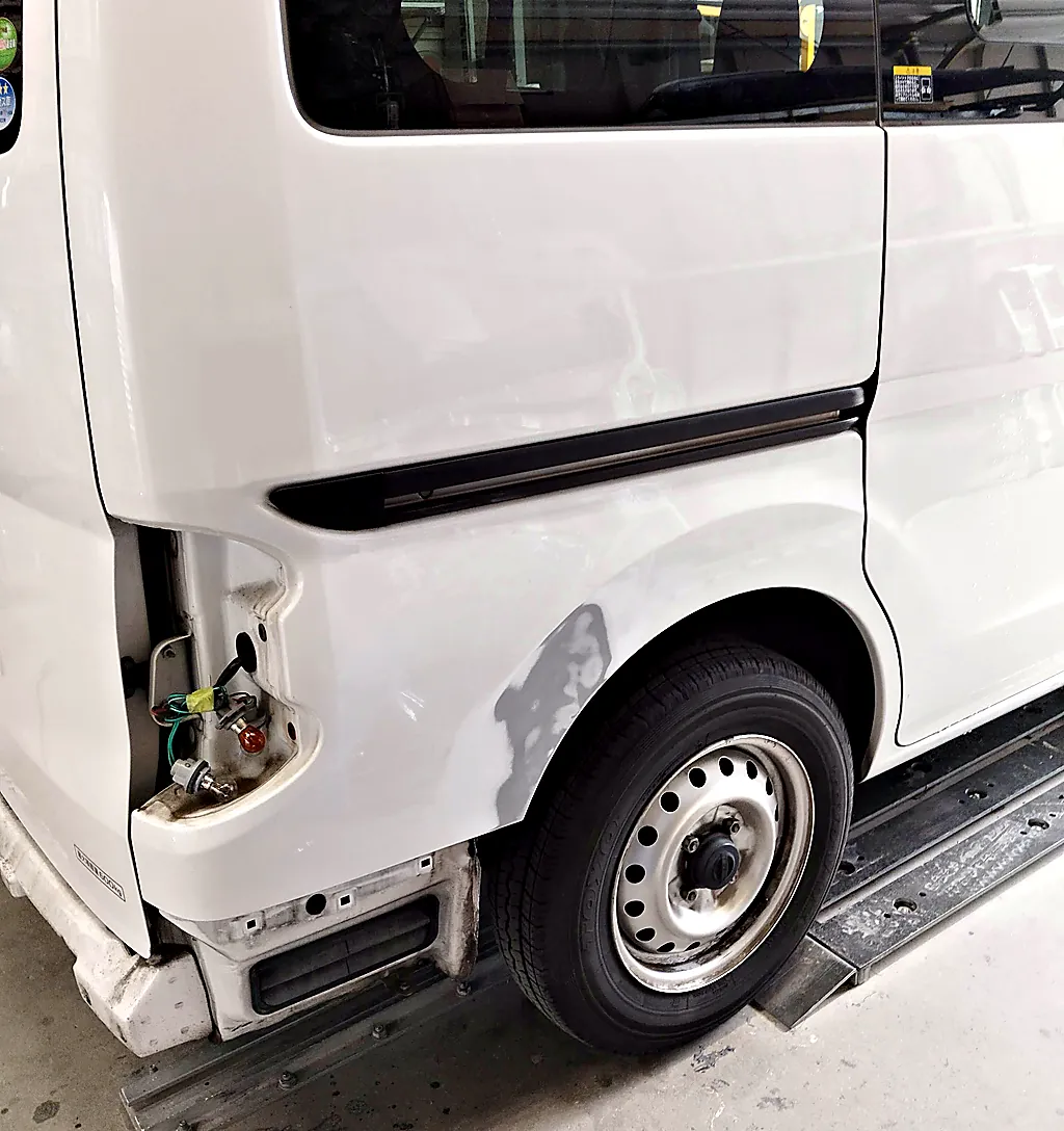 右テールランプを外したNV200バネット バンの右リヤクォーター。後輪のアーチの後ろを研いだ跡