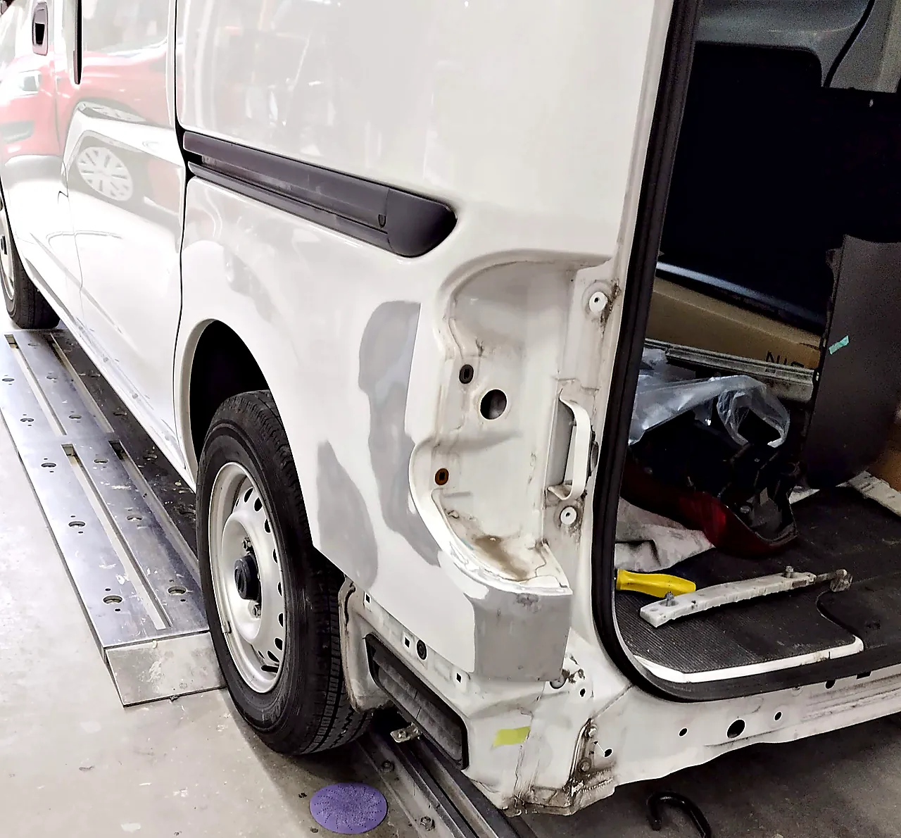 チェーンで引いたあと、NV200バネット バンの左リヤクォーターのランプまわりと下の角を研いだ状態（灰色が研いだ跡）