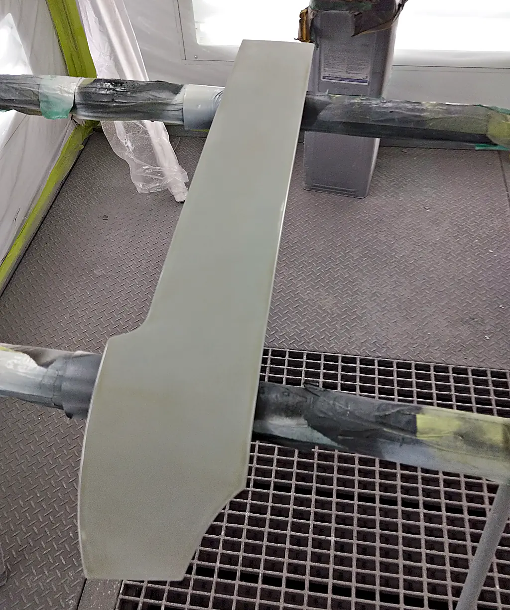 塗装ブースのスタンドに載せた、ソリオのクォーターに付く細長いカバー（まだ車の色が塗られていない状態）