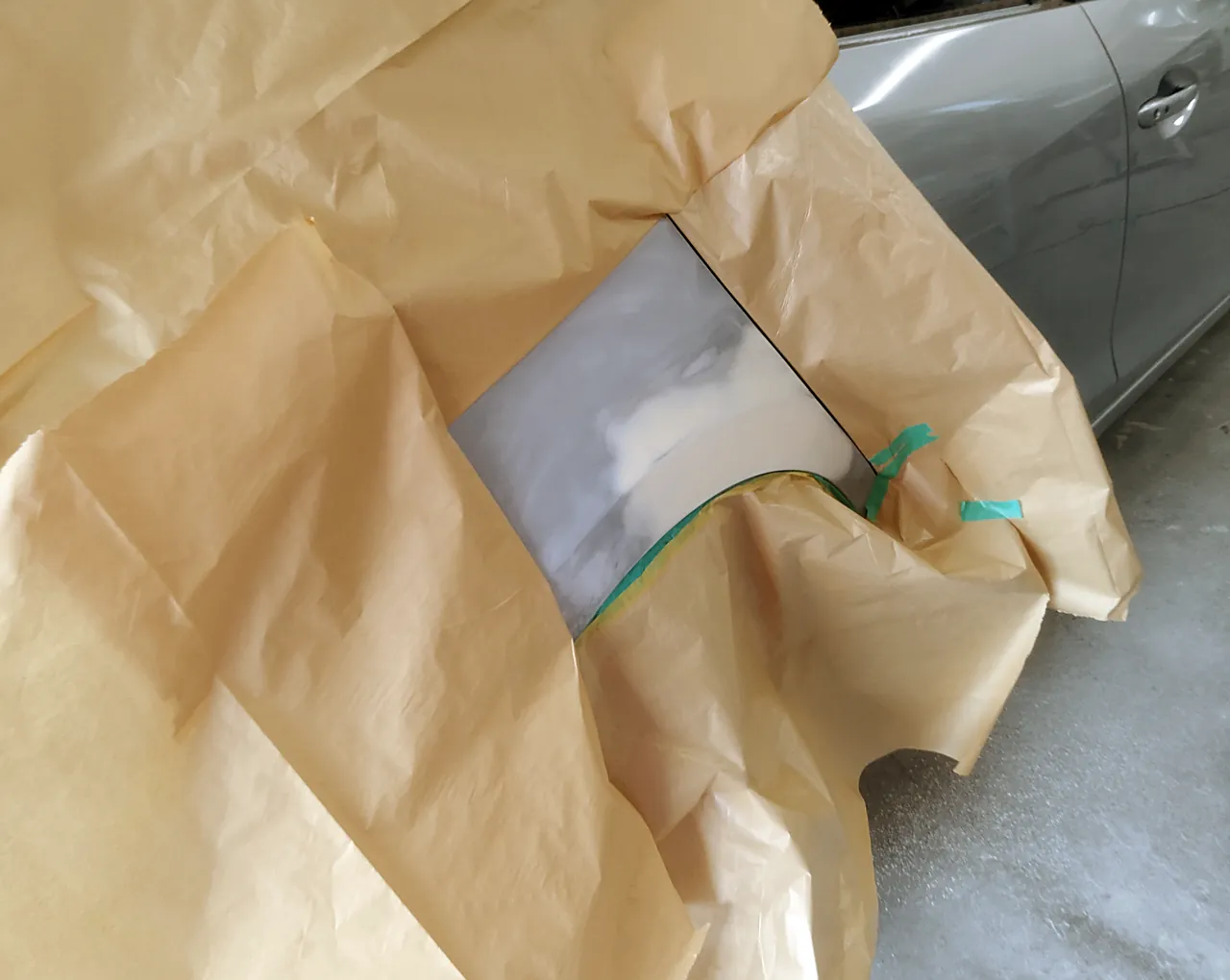 アクセラの右リヤクォーター。研いだ所とパテのまわりだけを出し、紙で大きく覆ったところ(サフェーサーの前)