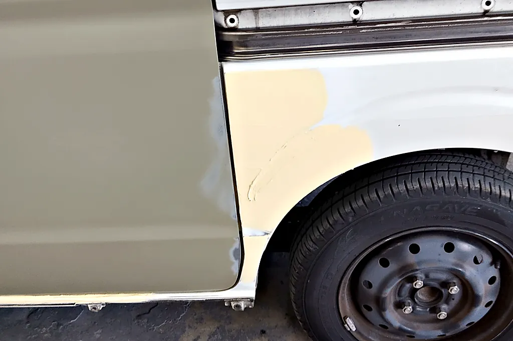 エブリイワゴンの後輪の前のクォーターの下のほうに付けたクリーム色のパテ。左は車に付けた新しいスライドドア
