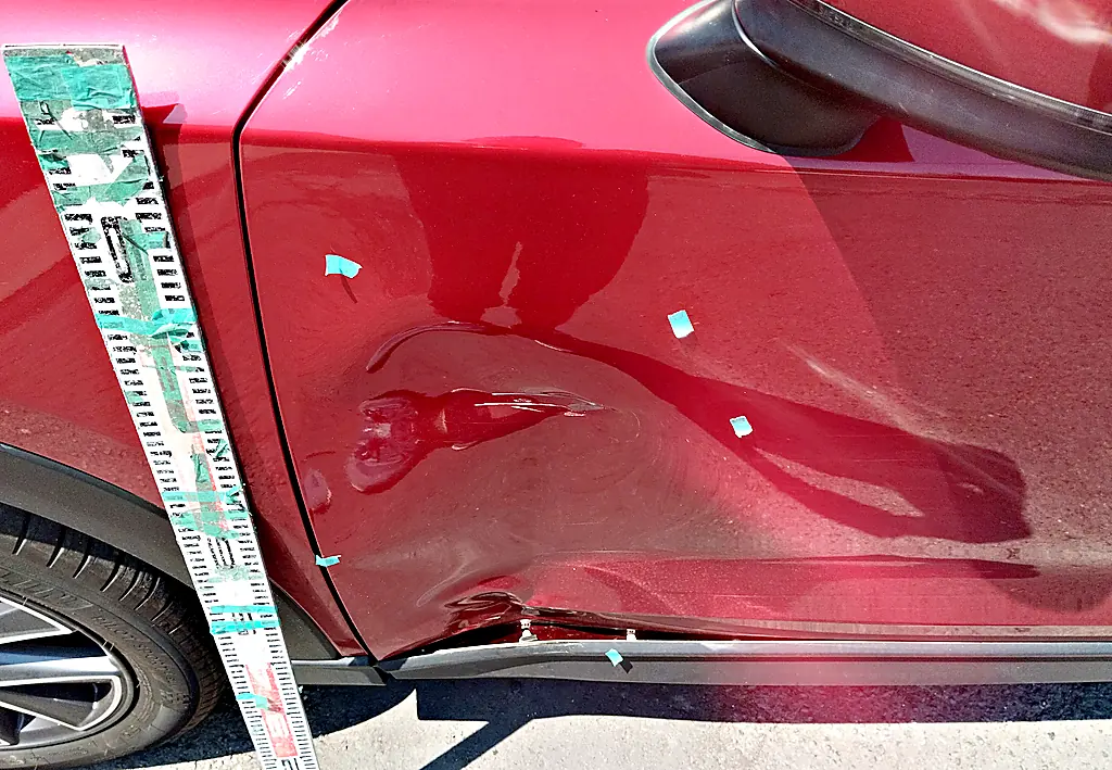 CX-5の左フロントドアの下の前寄りに入った、線のように鋭いへこみと擦り傷（修理前・目盛りの棒と目印のテープ）