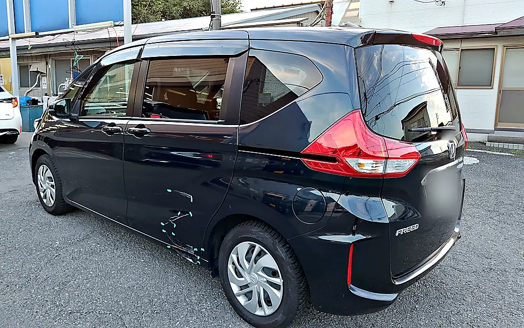 お預かりしたホンダ フリード(2代目)を左後ろの斜めから。スライドドアの後ろの下とサイドシルに緑のテープと擦り傷(修理前)