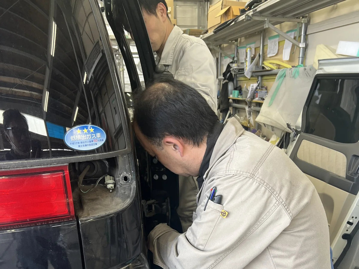 先輩と2人でドアの内部を確認しながら作業している様子